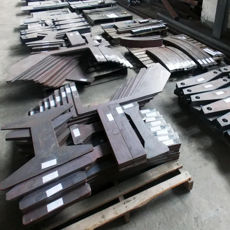 Stacks of cut steel plate parts on pallets in a workshop